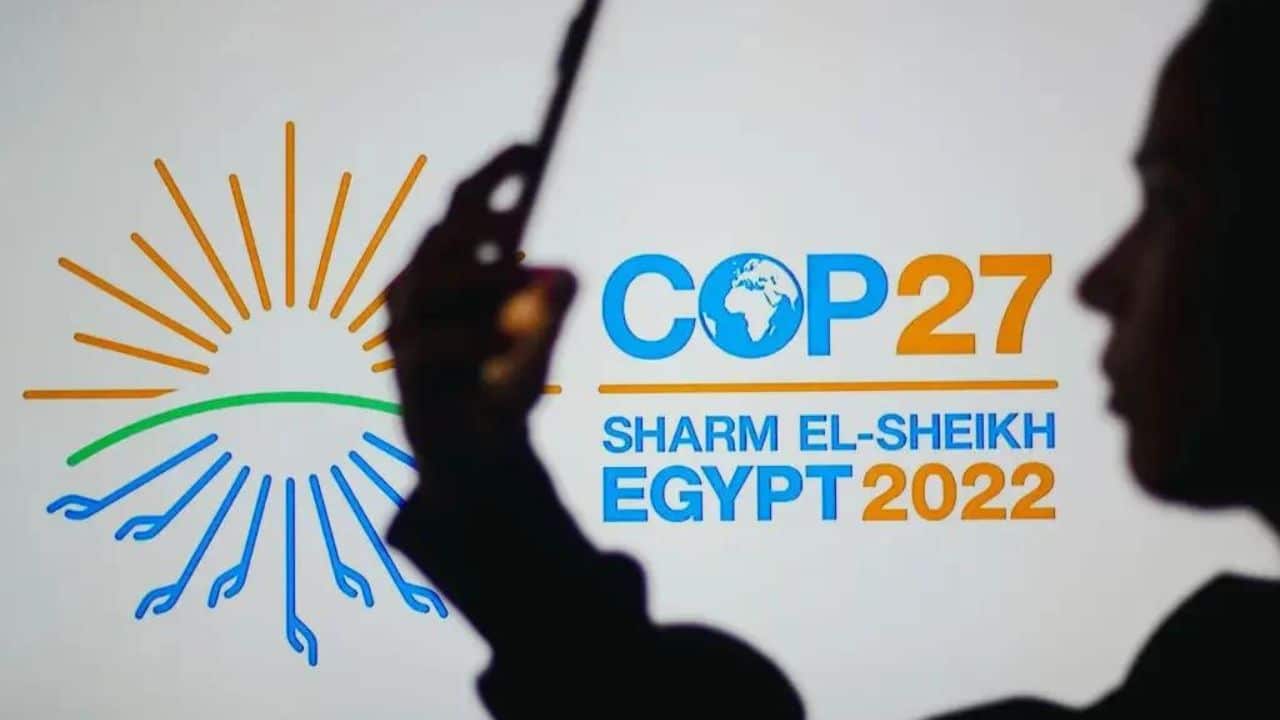 Silhueta de uma mulher diante do logotipo oficial da COP27